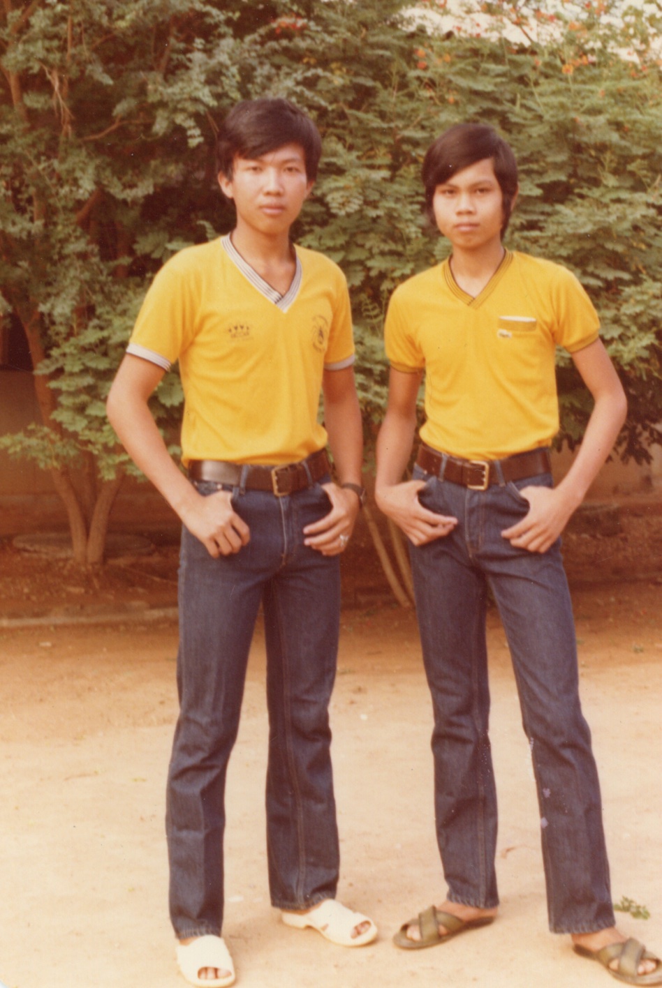 Two young men stand next to each other in matching outfits