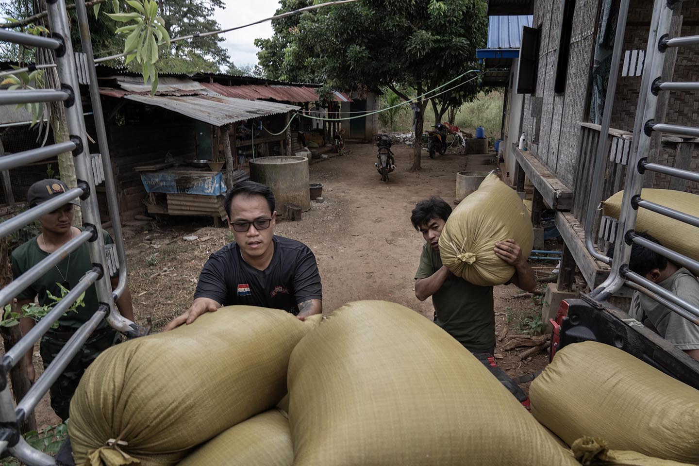 Two men stack large bags of rice