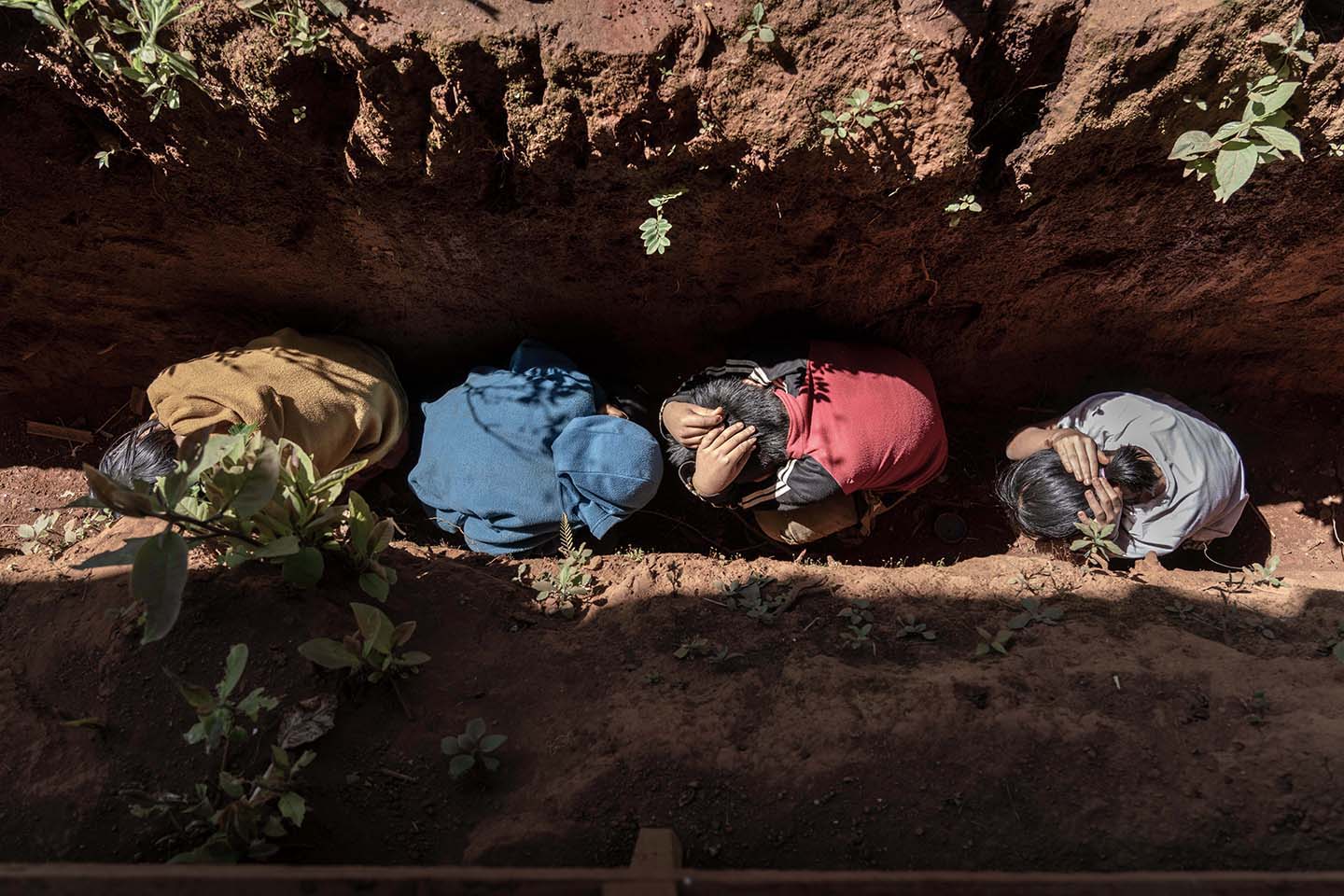 Four children huddle in a ditch