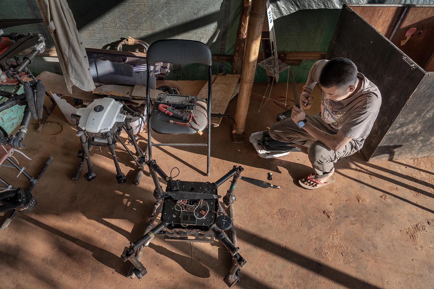 Drone pilot works on two drones on the floor