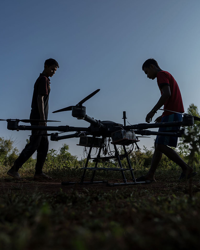 Two people move near a drone to prepare it for flight