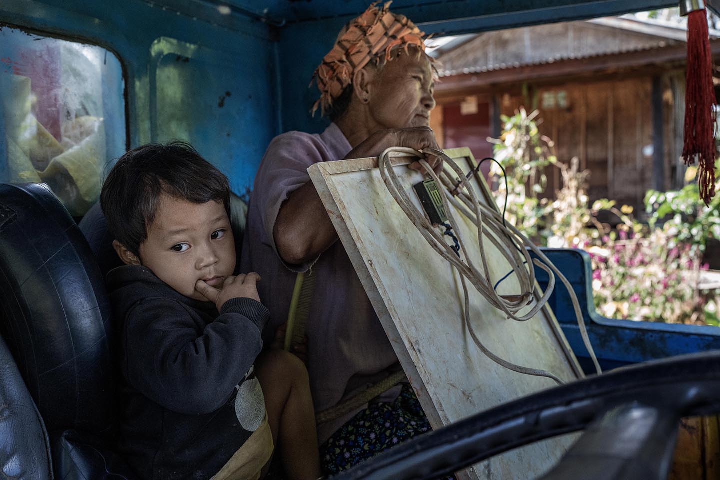 A little boy and elderly woman sit in a blue vehicle