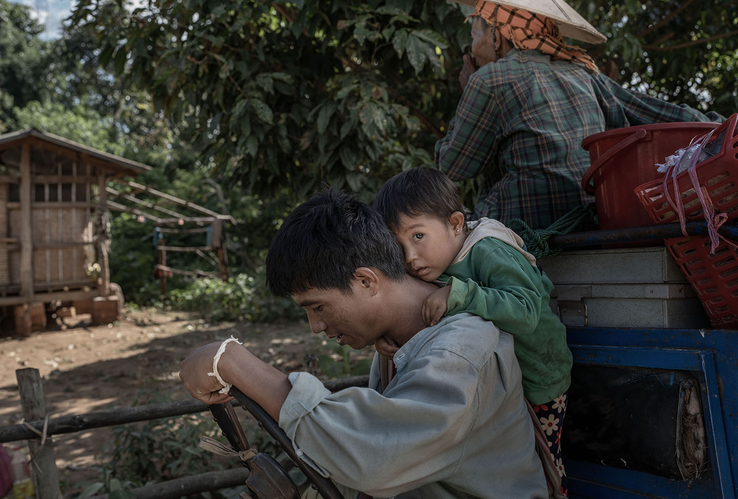 A small child hangs from a man's back while leaning their face into his neck