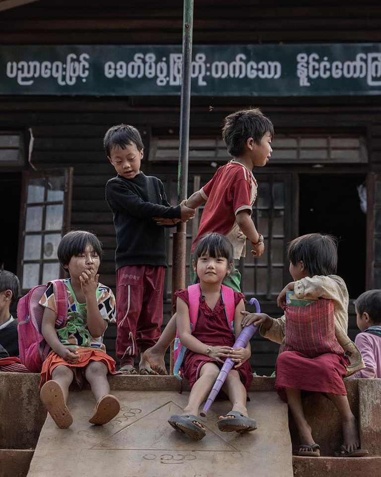 Children gather around a pole with their book bags on