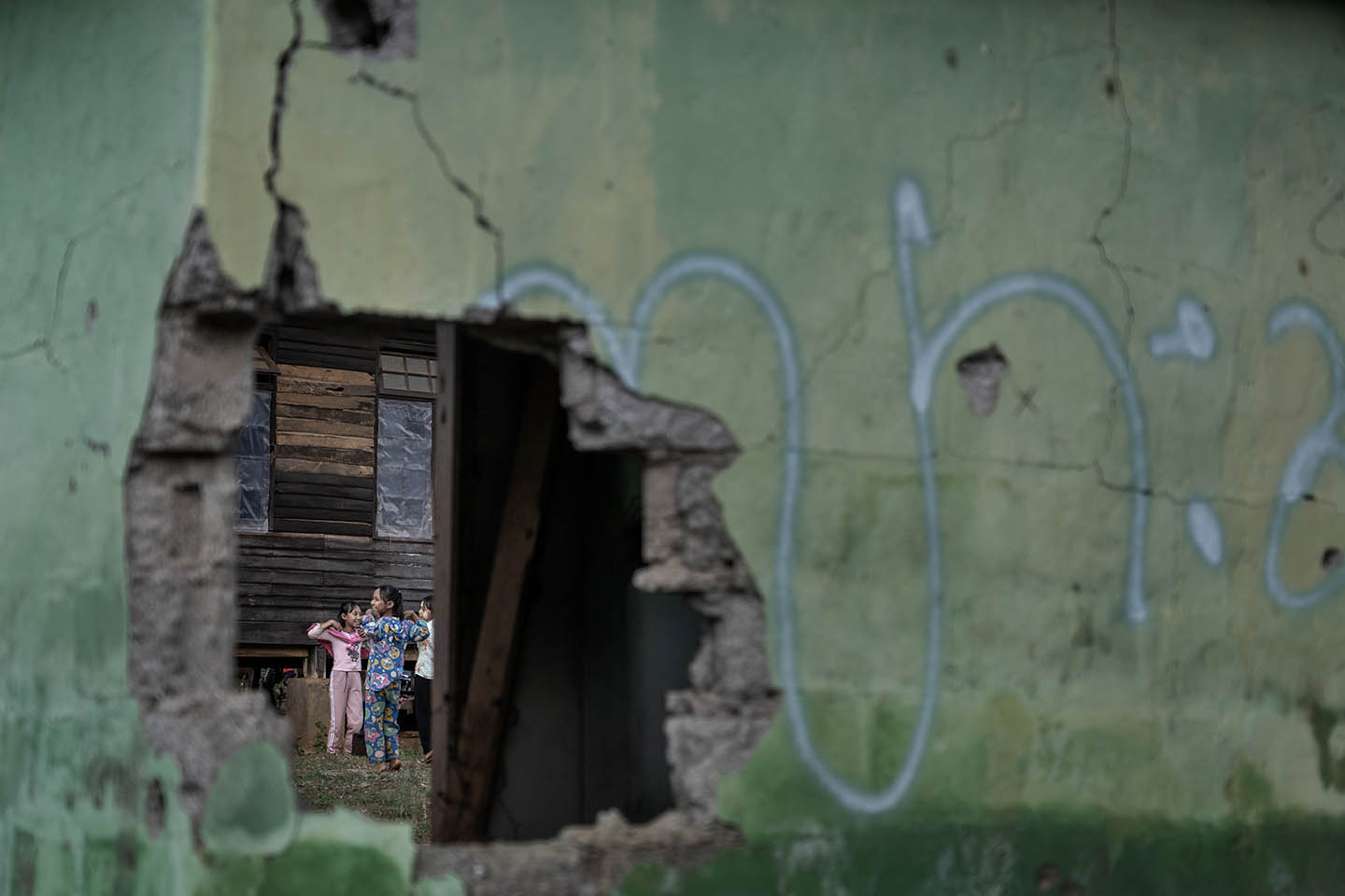 Chidren are seen dancing through a hole in a wall