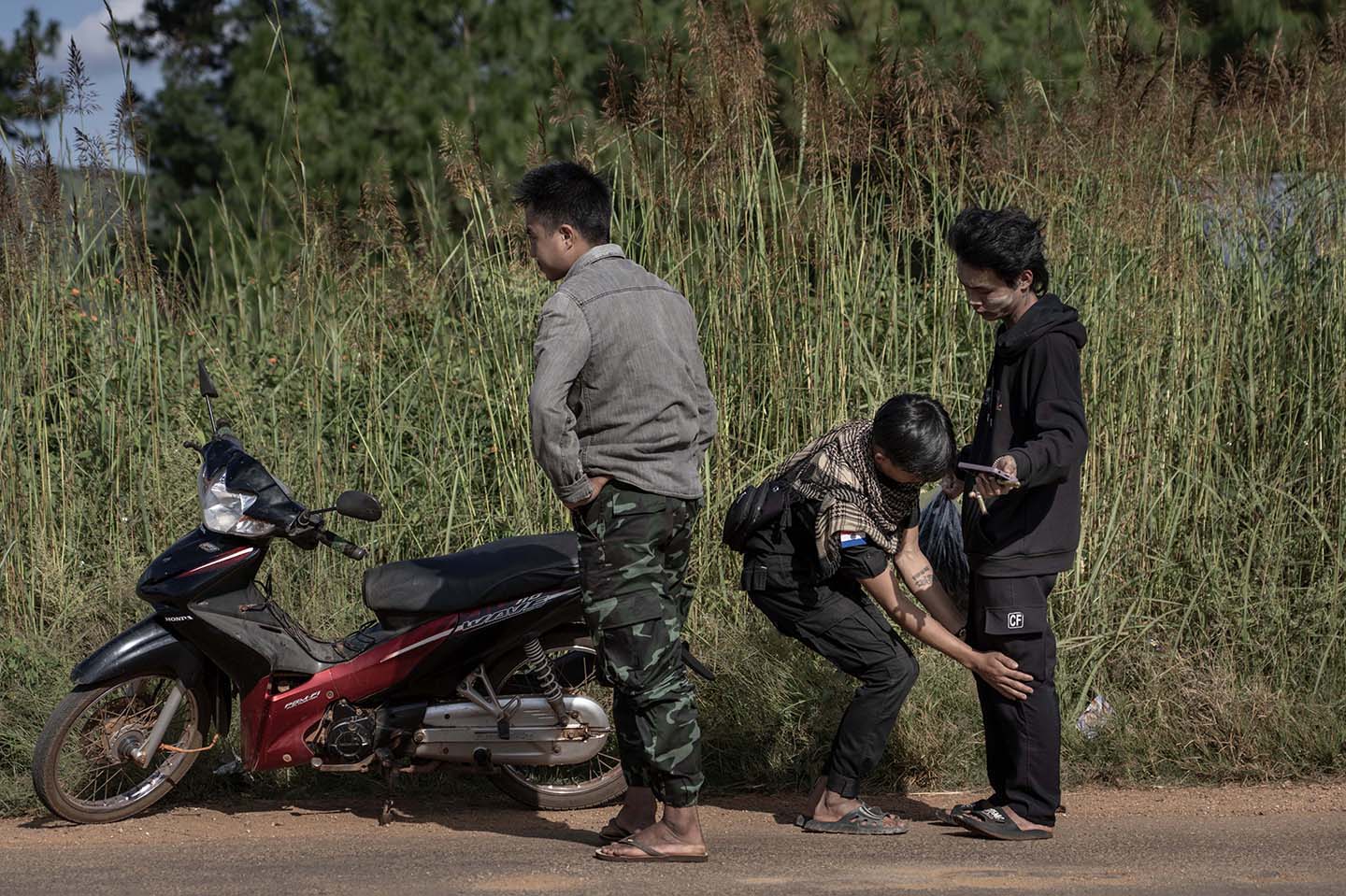 An officer pats down an individual on the side of a road