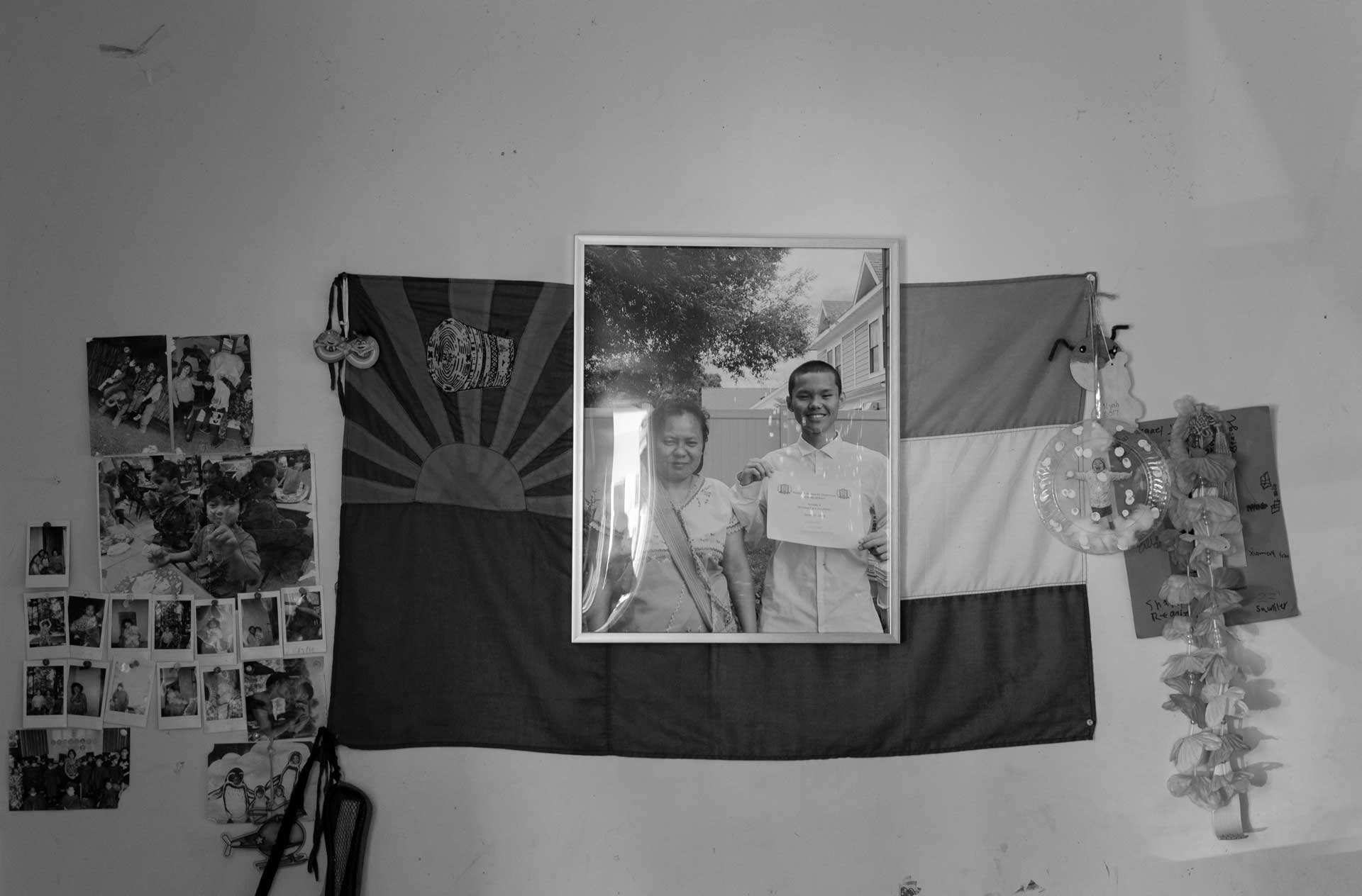 A photo of Nyah Mway and his mother, Chee War, posing after his middle school graduation hangs on the wall of the family’s home, alongside a Karen flag and other memorabilia in Utica, New York, July. 07, 2024.