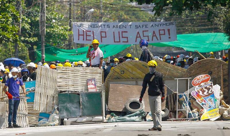 Protestors stand on a makeshift barricade as they prepare to face off against security forces during a demonstration in Yangon. (AFP)