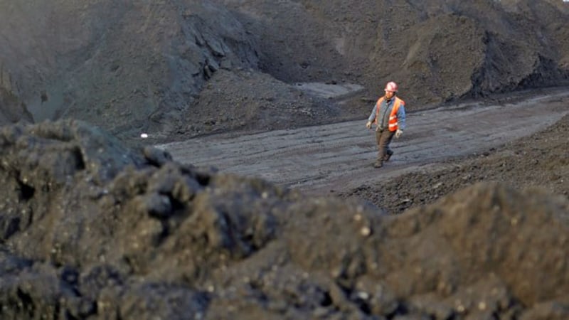 A worker walks past coal piles at a coal coking plant in Yuncheng, northern China's Shanxi province, Jan. 31, 2018.