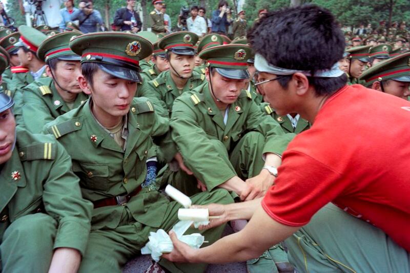 1989年5月15日，杨尚昆主席会见苏联领导人戈尔巴乔夫时，一名绝食抗议的中国学生给人民大会堂前的解放军士兵送冷饮。（亨丽埃特/法新社）