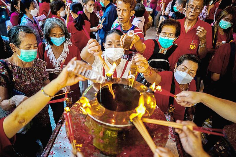 People light joss sticks for the 2023 Lunar New Year at a Chinese temple in Bangkok.