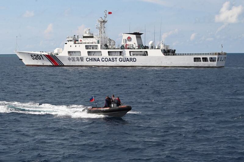 Philippine coast guard personnel speed past a China Coast Guard vessel on a rigid inflatable boat after conducting a survey at Second Thomas Shoal in the disputed South China Sea, April 23, 2023. Credit: AFP