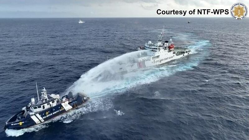 A China Coast Guard ship (R) deploying water cannon at the Philippine Bureau of Fisheries and Aquatic Resources vessel BRP Datu Pagbuaya (L) near Scarborough Shoal in disputed waters of the South China Sea.