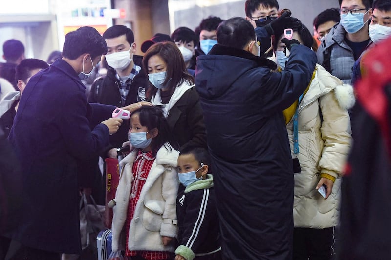 Staff members check the temperatures of passengers arriving on a train from Wuhan to Hangzhou, China, Jan. 23, 2020. (AFP)