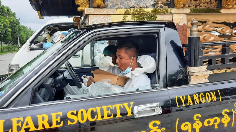 Volunteers from a group providing free funeral services during the COVID-19 outbreak take a break for lunch at a cemetery in Yangon, July 21, 2021. RFA