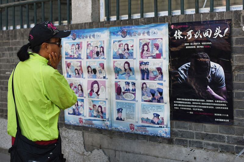 在北京的街头墙上粘贴的警告当地居民注意外国间谍的宣传漫画和海报。（法新社）