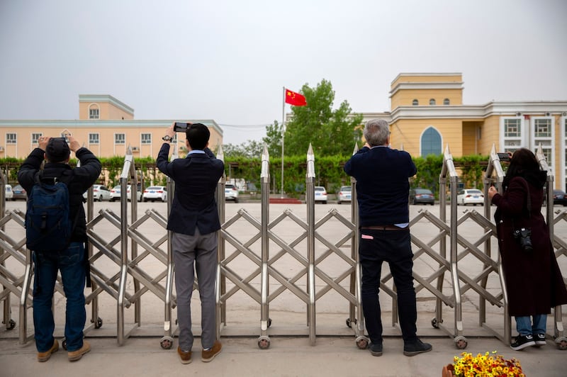 Journalists take photos outside a location identified in early 2020 as a re-education facility, which the Chinese government asserts is home to a veterans' affairs bureau and other offices, in western China's Xinjiang Uyghur Autonomous Region, during a trip organized by the government for foreign journalists, April 22, 2021. Credit: AP Photo