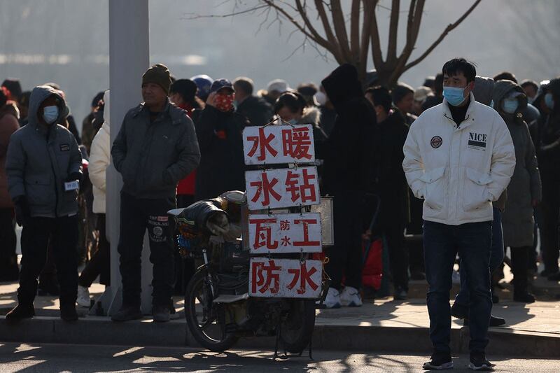 图为辽宁沈阳一面招聘广告牌旁的应聘民工（法新社）