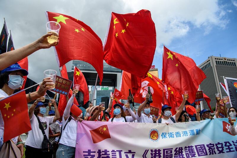 Pro-China supporters display Chinese and Hong Kong flags as they raise a toast with champagne during a rally near the government headquarters in Hong Kong, as China passed a sweeping national security law for the city, June 30, 2020.