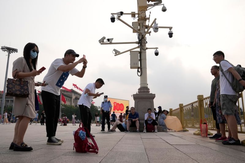 2021 年 7 月 15 日，游客在北京天安门广场监控摄像头附近拍照，一名警察在旁观看。(照片来源：Ng Han Guan/美联社)