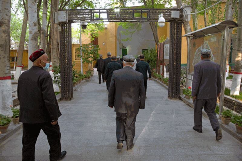 Uyghurs and other members of the faithful walk under an arch with security cameras as they leave the Id Kah Mosque after prayers in Kashgar, northwestern China's Xinjiang region, as seen during a government organized trip for foreign journalists, April 19, 2021. Credit: Associated Press