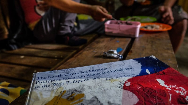 A book about an international court case in a territorial dispute over Scarborough Shoal sits on a bench in Johnny Sonny Geruela's home as he and his wife share a meal, Sept. 6, 2019.