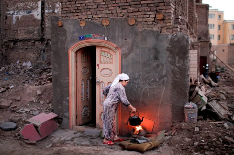 A woman cooks next to the remnants of neighboring houses demolished as part of a building renovation campaign in Kashgar Old City in northwestern China's Xinjiang region, Aug. 3, 2011. (Carlos Barria/Reuters)