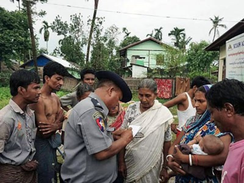 Myanmar Hindus speak to a Myanmar policeman at a makeshift camp after fleeing violence in Rakhine state's Maungdaw township, Aug. 30, 2017.