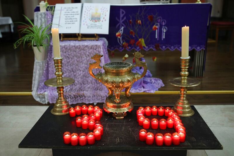 Lit, red votive candles in the shape of "39" sit on a black altar. Lit, white candle sticks in golden holders are to either side of the formation.