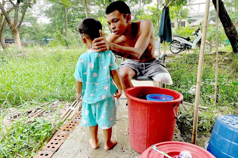 Ko Phyo prepares to take a shower with his 2-year-old son, Paing Phyo Oo, at his home. "I feel terrible when he asked, 'Dad, where's your leg?'," Ko Phyo says. "So, I replied, 'A dog's eaten my leg but it will grow later.' And he still believes it." (REUTERS)