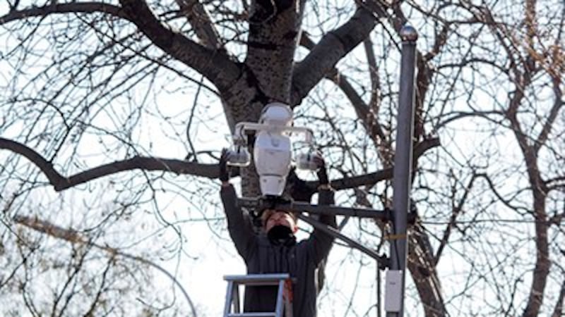 A worker installs a security camera pointed at a pedestrian walk way in Beijing, Dec. 11, 2017. Credit: AP Photo