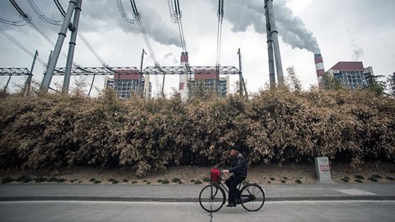 A man rides a bike past a coal-fired power plant operated by China's Shanghai Waigaoqiao Electric Power Generating Company Ltd. in Shanghai, March 22, 2016.