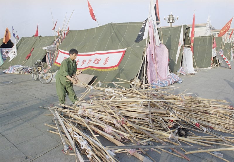 1989年6月1日，北京大学的一名学生在天安门广场收集竹子，搭建帐篷以遮蔽炎热。（美联社）