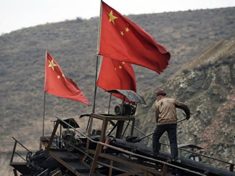 A Chinese worker clears a conveyor belt used to transport coal near a coal mine in Datong, northern China's northern Shanxi province, Nov. 20, 2015.