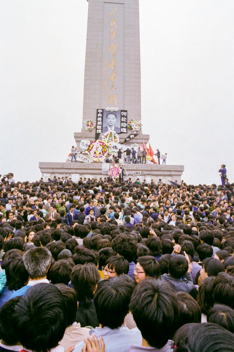 1989年4月19日，数千人在未经授权的情况下，聚集天安门广场人民英雄纪念碑前悼念胡耀邦。花圈上方摆放着前中共领导人、自由派改革家胡耀邦的肖像。（亨丽埃特/法新社）