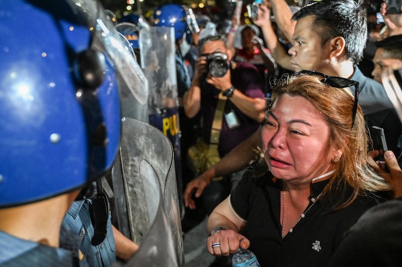 A supporter of former Philippine president Rodrigo Duterte reacts while facing police outside Villamor Air Base, where he is currently being held according to his political party, in Pasay, Metro Manila on March 11, 2025. Duterte was arrested on March 11 in Manila by police acting on an International Criminal Court warrant tied to his deadly war on drugs. The 79-year-old faces a charge of "the crime against humanity of murder", according to the ICC, for a crackdown that rights groups estimate killed tens of thousands of mostly poor men, often without proof they were linked to drugs. (Photo by Jam STA ROSA / AFP)