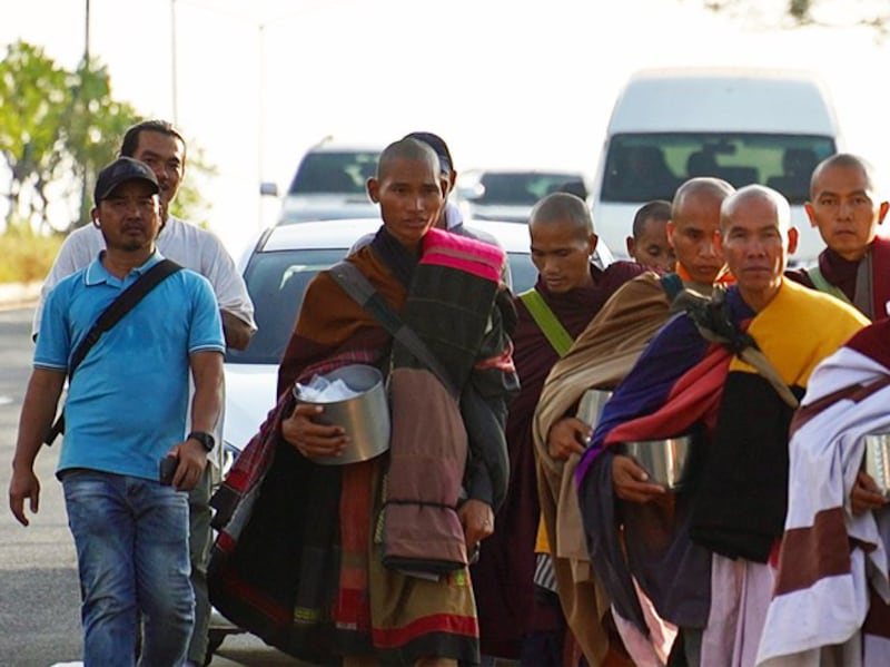 Vietnamese monk Thich Minh Tue is followed by his bodyguard Doan Van Bau, left, and a logistics pickup truck, as he walks through Thailand on his way to India, Jan. 2025.