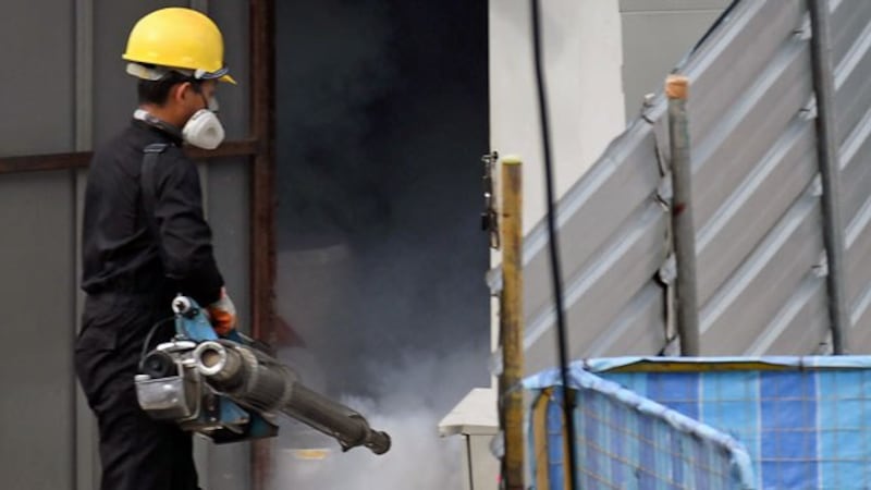 A worker wearing a protective face mask fumigates a construction site to prevent the spread of dengue during the coronavirus pandemic, in Singapore, April 17, 2020.