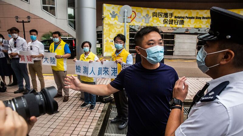 2020年8月2日，香港民主派政党「新民主同盟」区议员前往香港医管局抗议，反对中国协助在港进行武汉肺炎全民普筛，香港大埔区议会区议员关永业先生（右二）同警察交谈。（AFP）