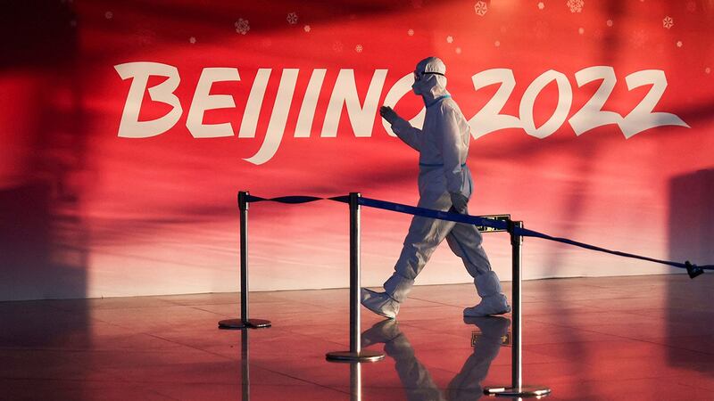 A staff member walks pass a sign for the 2022 Winter Olympics in Beijing, in a file photo. Reuters