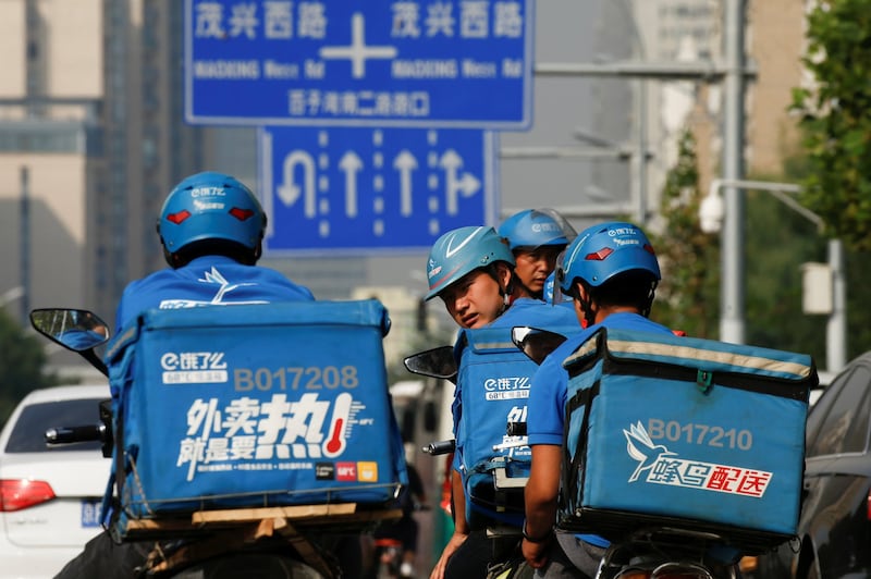 图为穿着蓝色制服的外卖送餐人员奔跑于城市的大街小巷。（路透社）