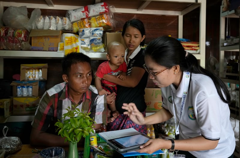 A census enumerator, right, asks questions to a family in Naypyitaw, Myanmar Tuesday, Oct. 1, 2024 as the country holds a national census to compile voter lists for a general election. (AP Photo/Aung Shine Oo)