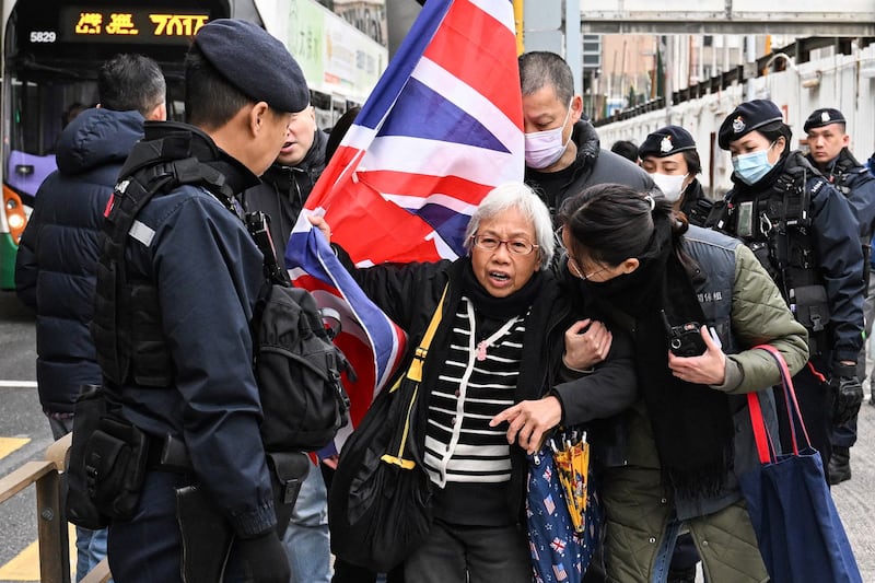 Police stop activist Alexandra Wong [center], also known as Grandma Wong, as she carries Britain's Union Jack outside the West Kowloon court ahead of the trial for Jimmy Lai in Hong Kong on Friday, Dec. 22, 2023. (Peter Parks/AFP)