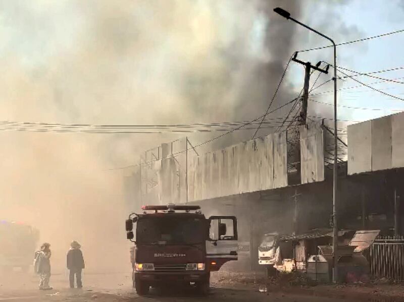 A fire truck sits outside a badly damaged commercial property as black smoke billows into the sky in Xay district of Oudomxay province in northern Laos, Feb. 14, 2025.