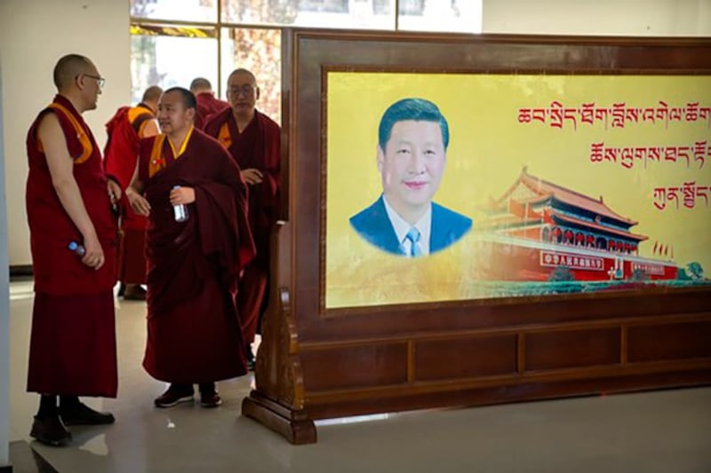 Monks stand near a mural featuring Chinese President Xi Jinping at the Tibet Autonomous Region Buddhist College near Lhasa in western China's Tibet Autonomous Region, May 31, 2021. (Mark Schiefelbein/AP)