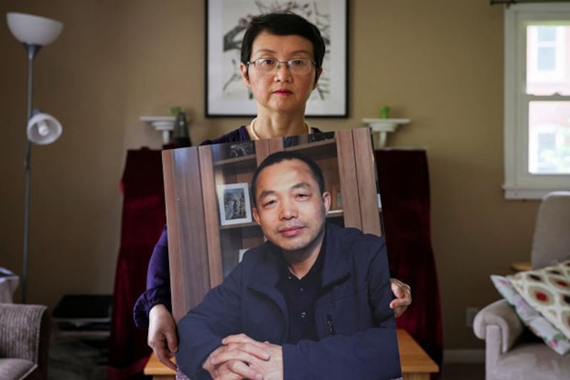 Luo Shengchun, wife of jailed Chinese human rights lawyer, Ding Jiaxi, poses with a photo of him at her home in Alfred, New York, July 28, 2022. (Brendan McDermid/Reuters)