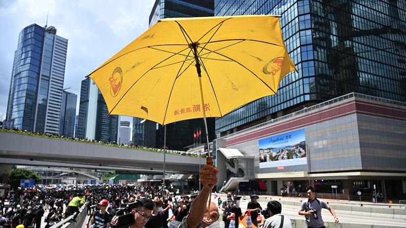 2019年6月21日，香港政府总部外，反送中示威者手举一把黄色雨伞。（法新社）