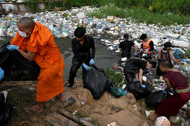 Volunteer students and Buddhist monks collect plastic waste from a sewage canal to set an example and educate people on proper plastic disposal in Phnom Penh on Oct. 28, 2023. (Tang Chhin Sothy/AFP)