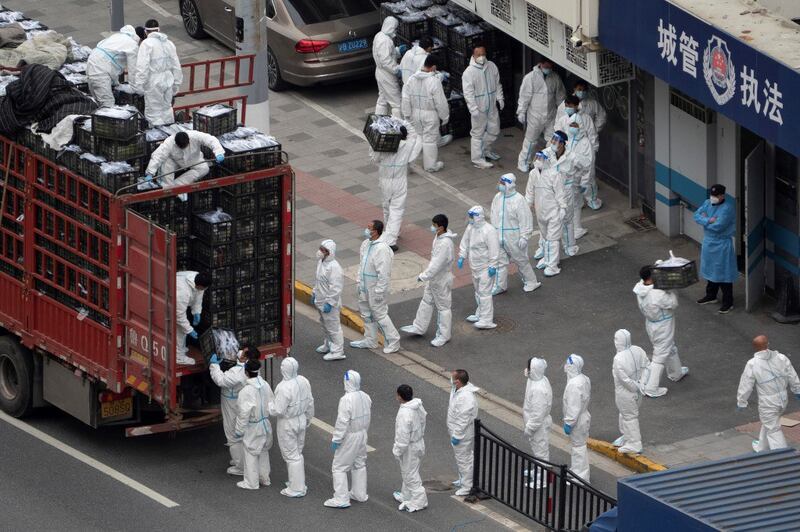 People wear personal protective equipment (PPE) as they transfer daily food supplies and necessities for local residents during the Covid-19 lockdown in Shanghai, April 5, 2022. Credit AFP