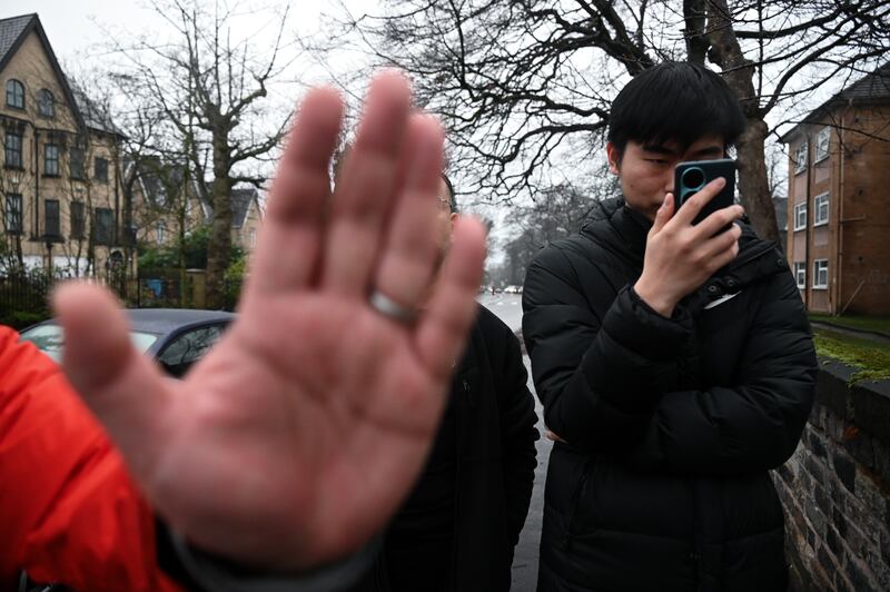 一名华裔男子从领事馆步出，在未有交代身分的情况下用手机近距离拍摄记者。